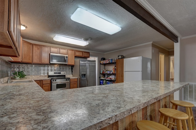 kitchen with sink, ornamental molding, tasteful backsplash, a kitchen bar, and stainless steel appliances