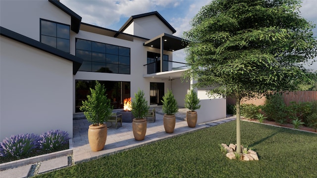 rear view of house featuring a balcony, a fire pit, a patio area, and a lawn