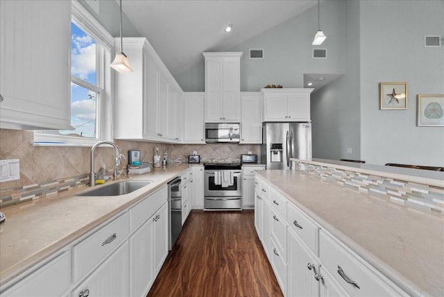 119 Velasco Shores Dr, Surfside Beach, TX 77541 - kitchen with stainless steel appliances, backsplash, white cabinetry, hanging light fixtures, and dark wood finished floors