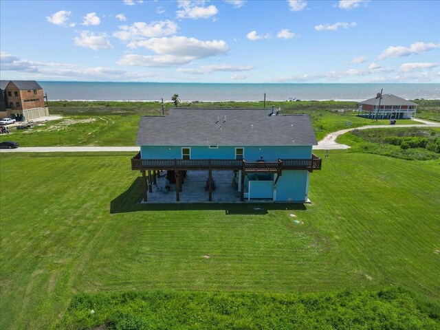 rear view of house with a lawn and a deck with water view