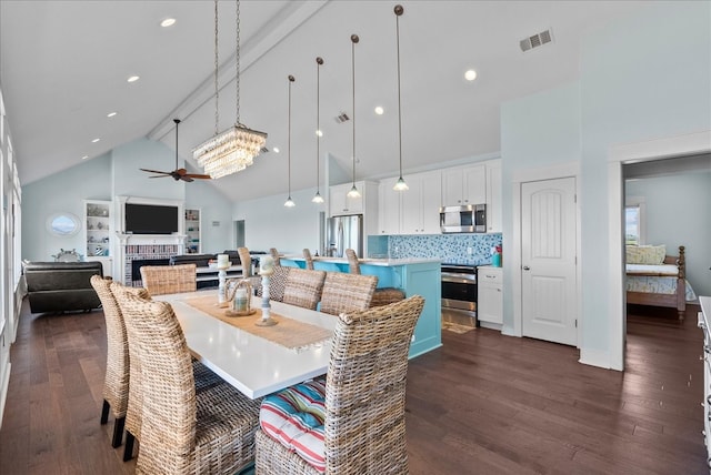 dining room featuring beamed ceiling, a tile fireplace, dark wood-type flooring, high vaulted ceiling, and ceiling fan