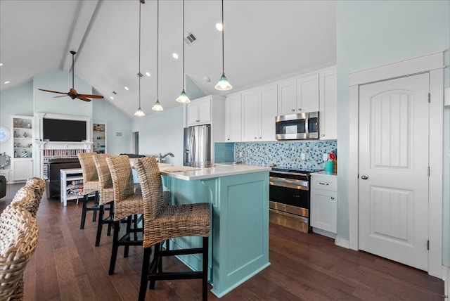 kitchen featuring dark hardwood / wood-style floors, appliances with stainless steel finishes, beam ceiling, hanging light fixtures, and ceiling fan