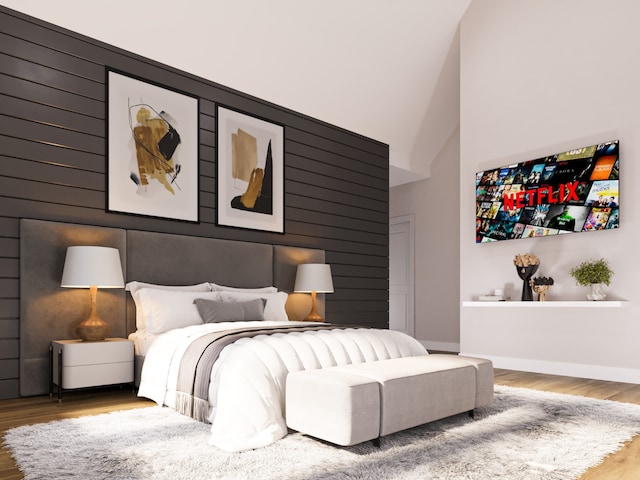 bedroom with wood-type flooring and high vaulted ceiling