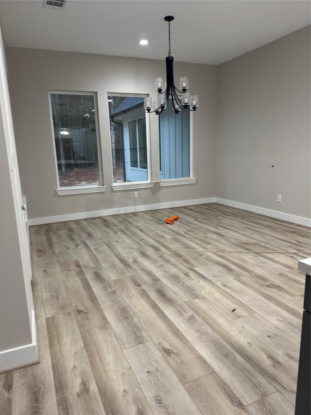 unfurnished dining area featuring an inviting chandelier and light wood-type flooring