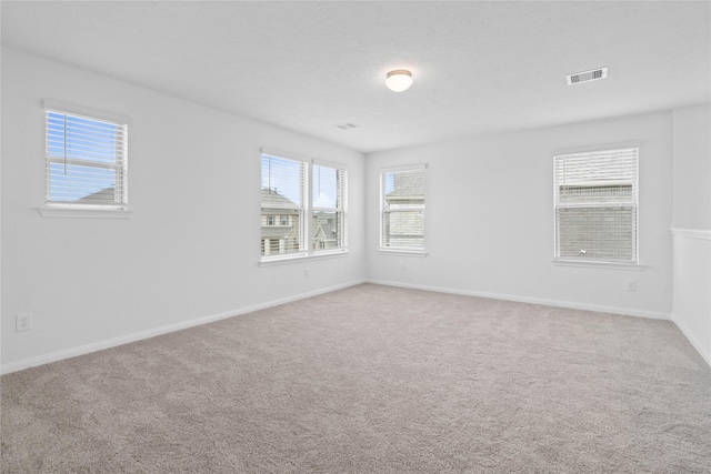 carpeted empty room featuring baseboards and visible vents