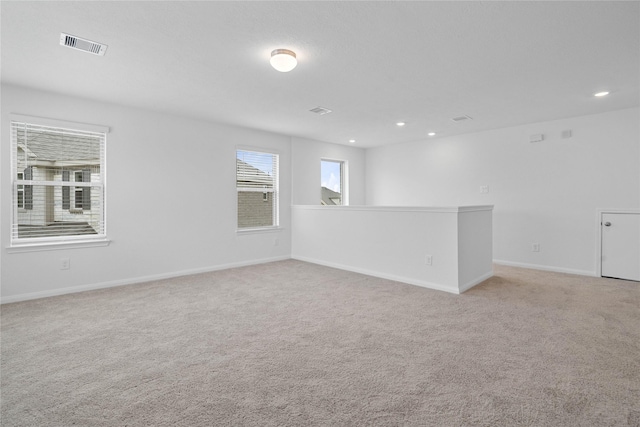 spare room with recessed lighting, light carpet, visible vents, and baseboards