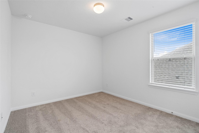 empty room with carpet floors, visible vents, and baseboards