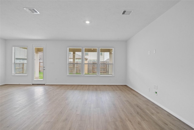 unfurnished living room featuring baseboards, visible vents, and light wood-style floors