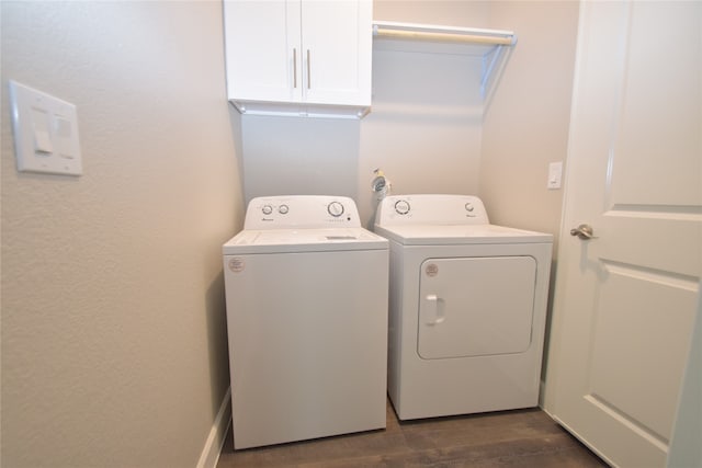 clothes washing area with dark wood-type flooring, washer and clothes dryer, and cabinets