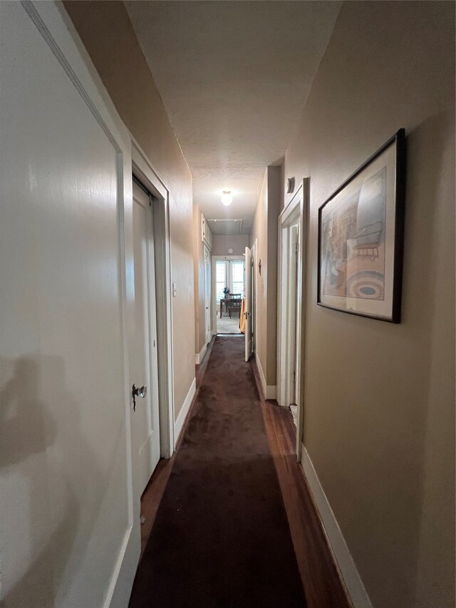 corridor featuring dark colored carpet