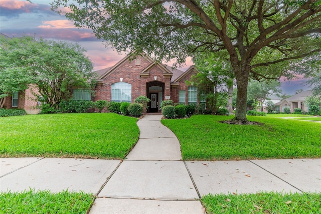 view of front of property with brick siding and a lawn