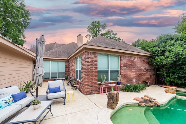 patio terrace at dusk featuring outdoor lounge area and an outdoor pool