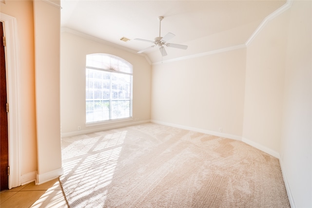 spare room featuring baseboards, visible vents, a ceiling fan, light colored carpet, and crown molding