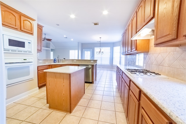 kitchen featuring white appliances, visible vents, a kitchen island, a peninsula, and under cabinet range hood