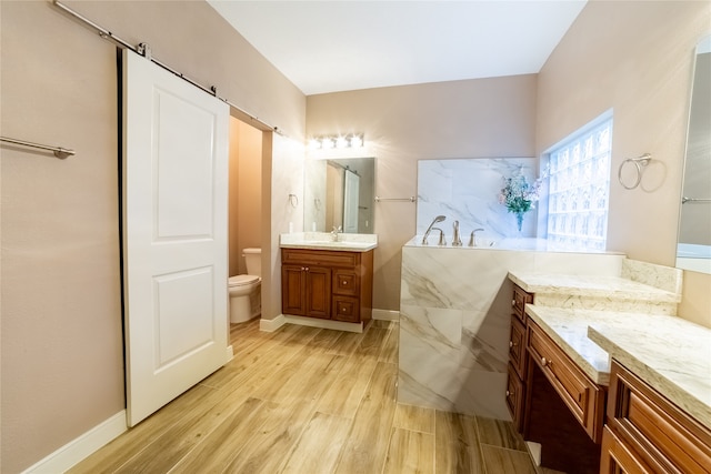 bathroom featuring vanity, wood finished floors, toilet, and baseboards