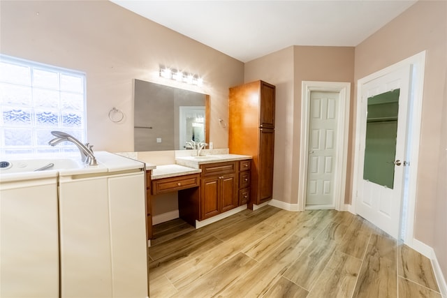 bathroom featuring baseboards, vanity, a bath, and wood finished floors