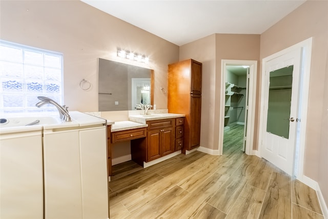 bathroom featuring a garden tub, wood finished floors, vanity, baseboards, and a walk in closet