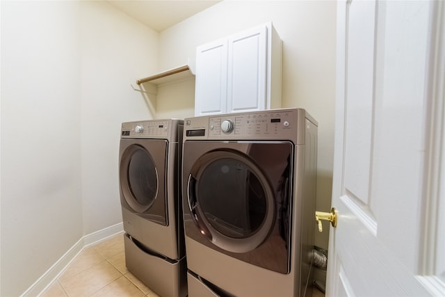 laundry room featuring washing machine and dryer, light tile patterned flooring, cabinet space, and baseboards