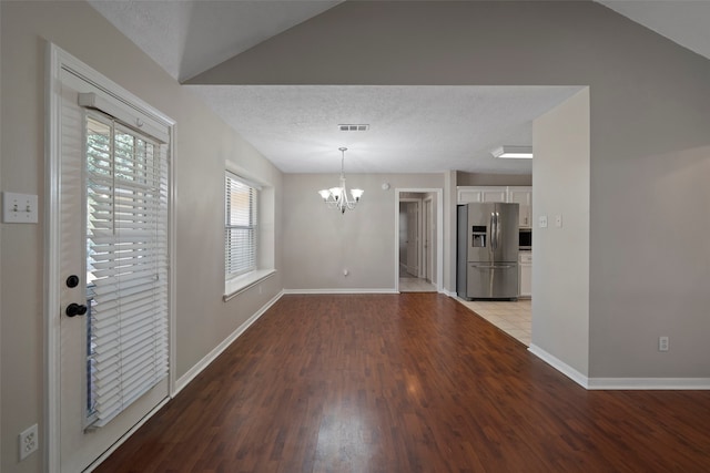 interior space featuring a chandelier, light hardwood / wood-style flooring, a textured ceiling, and vaulted ceiling