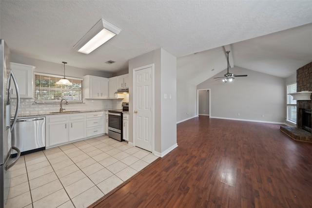 kitchen featuring light hardwood / wood-style flooring, sink, white cabinets, a brick fireplace, and appliances with stainless steel finishes