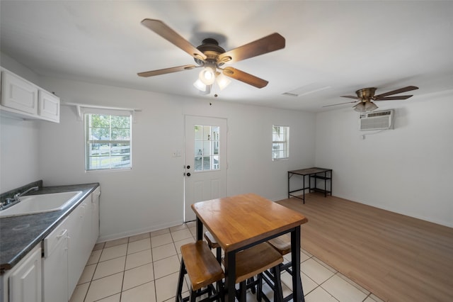 kitchen with a wall mounted AC, sink, white cabinetry, and light hardwood / wood-style flooring