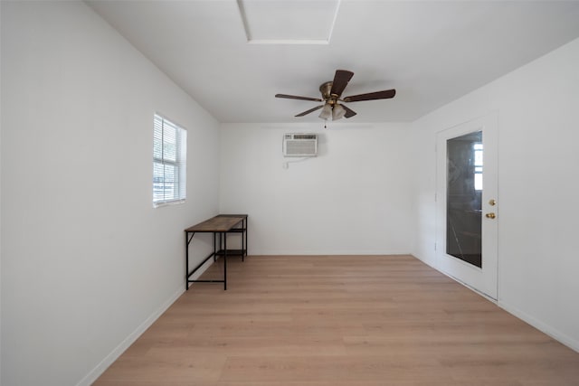 unfurnished room featuring an AC wall unit, light wood-type flooring, and ceiling fan