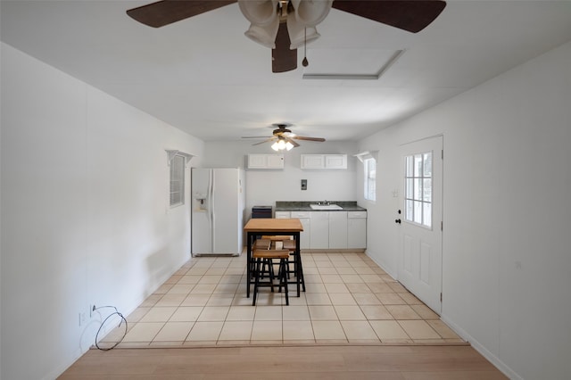 kitchen featuring white fridge with ice dispenser, a kitchen breakfast bar, sink, white cabinets, and ceiling fan