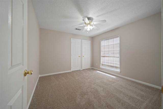 unfurnished bedroom featuring carpet floors, a textured ceiling, and ceiling fan