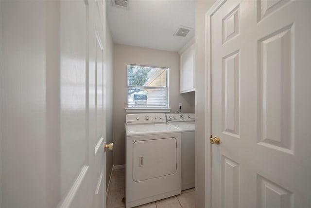 laundry room featuring cabinets, light tile patterned flooring, and washing machine and dryer