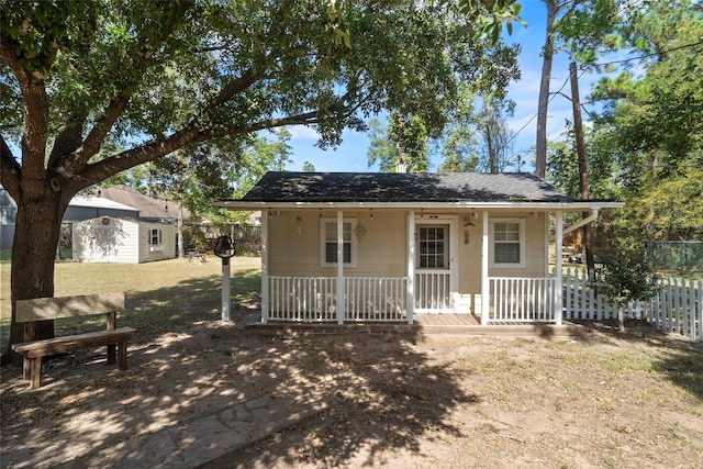 view of front of property featuring a front lawn, a shed, and a porch