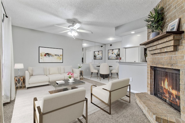 living room with a fireplace, ceiling fan, light colored carpet, and a textured ceiling