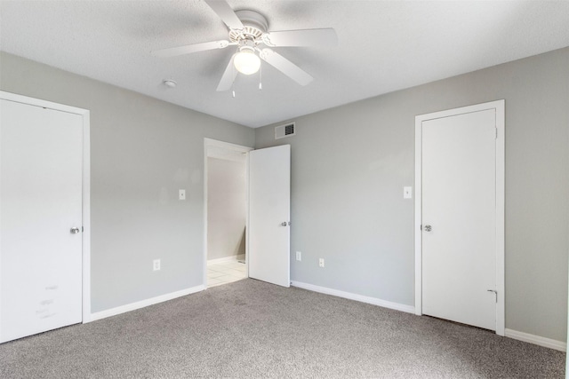 unfurnished bedroom with light carpet, a textured ceiling, and ceiling fan