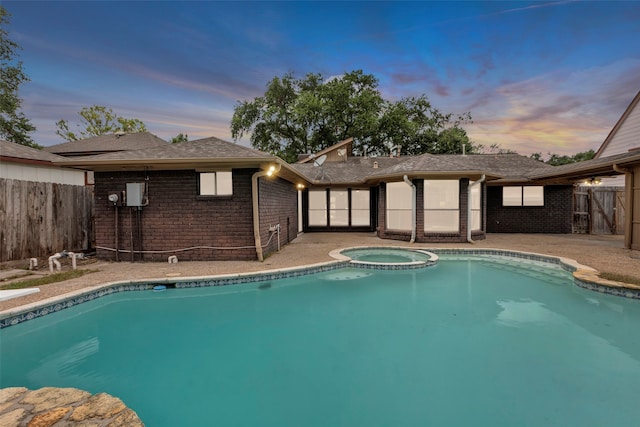 pool at dusk featuring an in ground hot tub