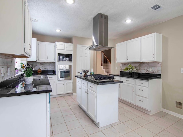 kitchen featuring appliances with stainless steel finishes, island exhaust hood, white cabinetry, and a kitchen island