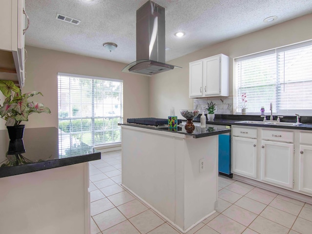 kitchen with island exhaust hood, sink, a center island, light tile patterned floors, and white cabinetry