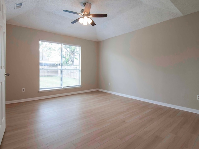 spare room with a textured ceiling, ceiling fan, light wood-type flooring, and vaulted ceiling