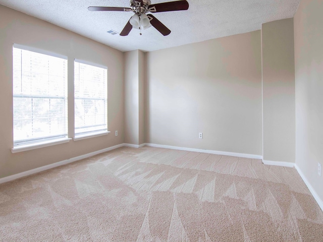 empty room with ceiling fan, a textured ceiling, and light colored carpet