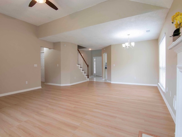 unfurnished room featuring a textured ceiling, ceiling fan with notable chandelier, and light wood-type flooring