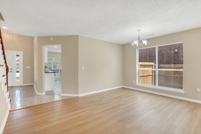 5635 Sage Manor Dr, Houston, TX 77084 - unfurnished room with light wood finished floors, a textured ceiling, a notable chandelier, and baseboards