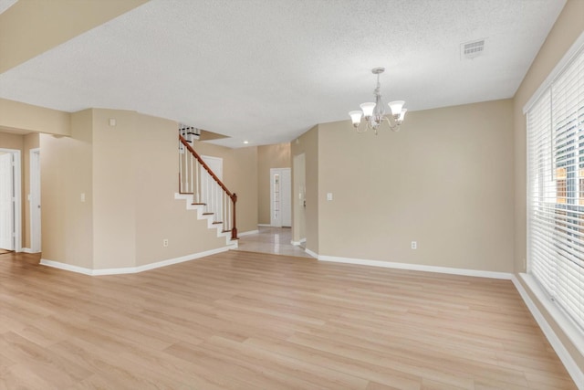 5635 Sage Manor Dr, Houston, TX 77084 - unfurnished room with a textured ceiling, visible vents, light wood-style floors, an inviting chandelier, and stairs