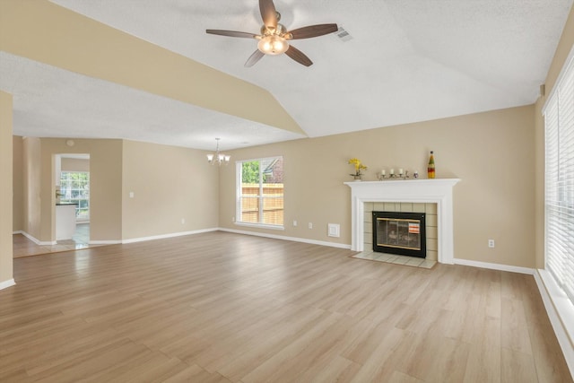 5635 Sage Manor Dr, Houston, TX 77084 - unfurnished living room featuring a tiled fireplace, light wood-style floors, visible vents, lofted ceiling, and ceiling fan with notable chandelier