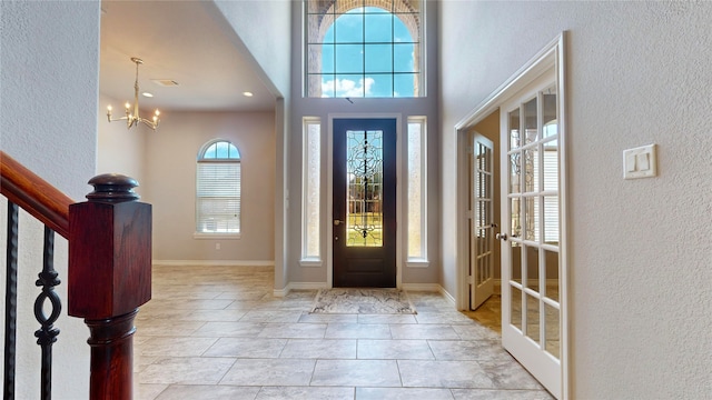 entryway featuring a high ceiling, french doors, a notable chandelier, and light tile patterned flooring