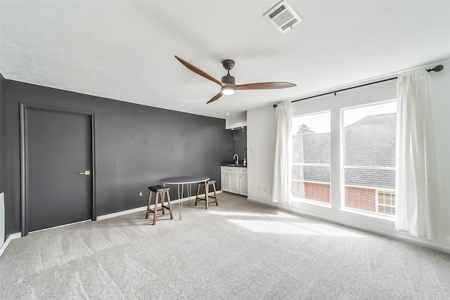 sitting room featuring a healthy amount of sunlight, ceiling fan, and light colored carpet