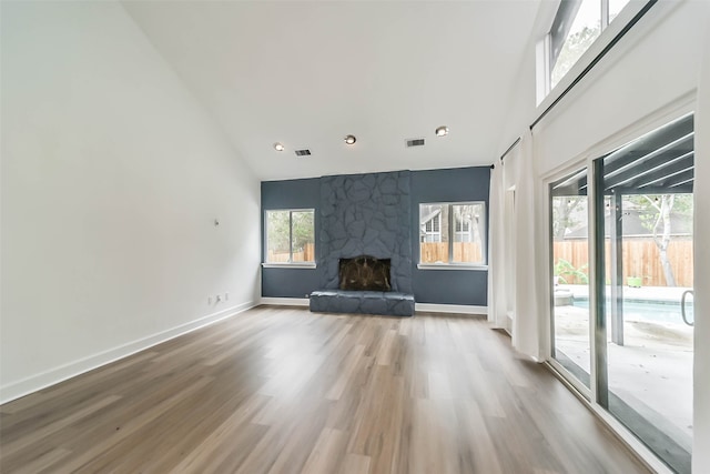 unfurnished living room featuring hardwood / wood-style flooring and a stone fireplace