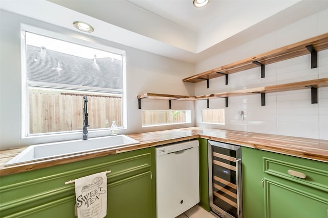 kitchen featuring butcher block countertops, white dishwasher, beverage cooler, sink, and green cabinetry