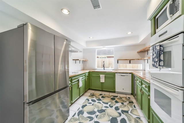 kitchen featuring green cabinetry, sink, white appliances, and light tile patterned flooring