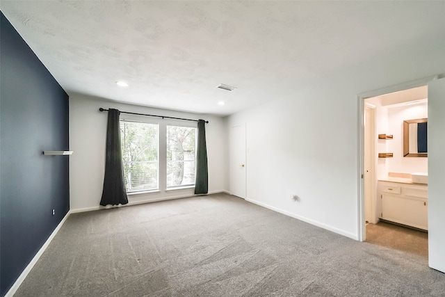 interior space featuring light colored carpet and ensuite bath