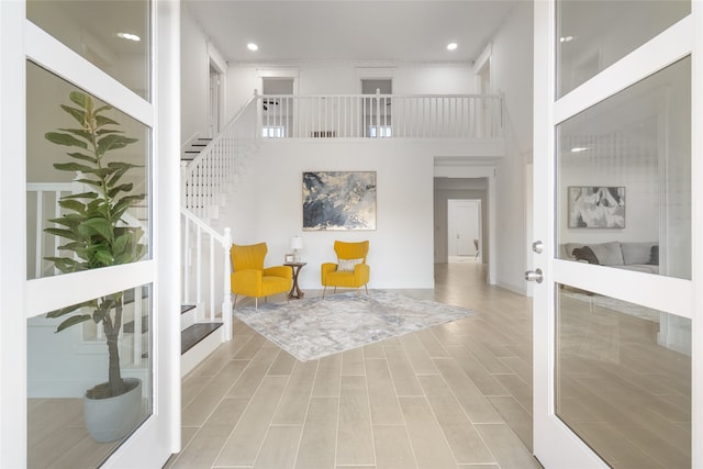 entryway with french doors, a towering ceiling, and light hardwood / wood-style flooring