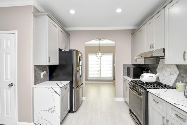 18306 Fresh Air Ct, Houston, TX 77084 - kitchen featuring crown molding, baseboards, light stone counters, under cabinet range hood, and stainless steel appliances