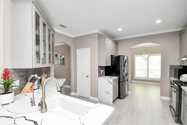 18306 Fresh Air Ct, Houston, TX 77084 - kitchen with black range with gas cooktop, arched walkways, a sink, baseboards, and glass insert cabinets